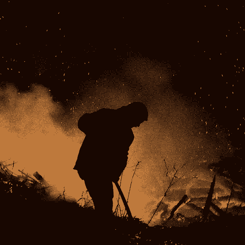 Silhouette of man tending large fire